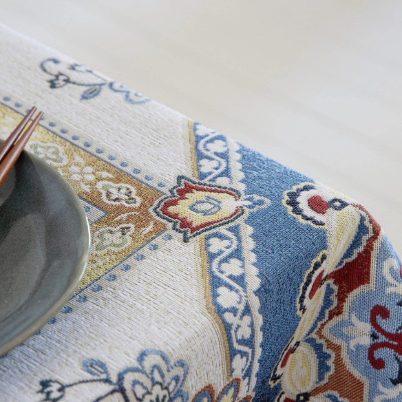 Mantel de mesa con diseño ornamental de inspiración mediterránea en tonos azul, rojo y beige sobre fondo claro